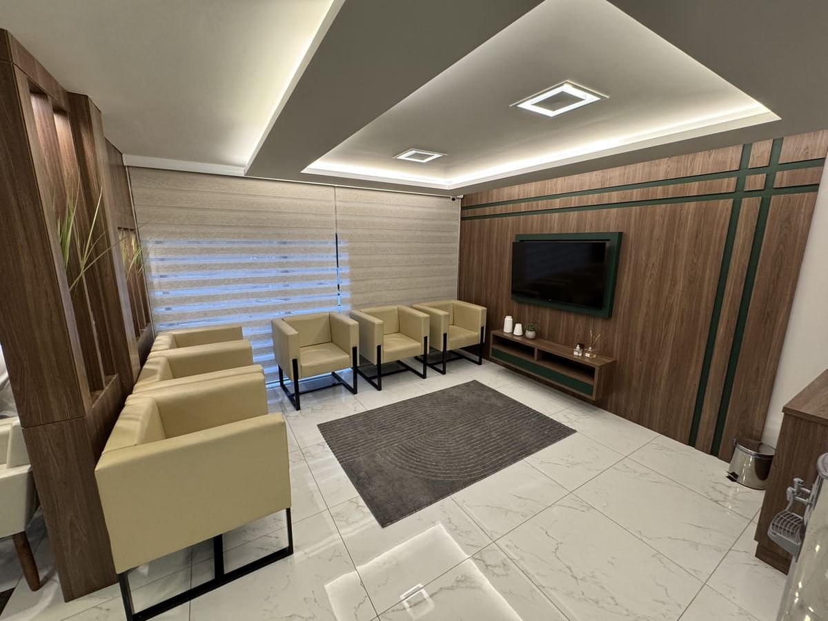 Recepção da Zure, com poltronas bege, painel de madeira e iluminação suave