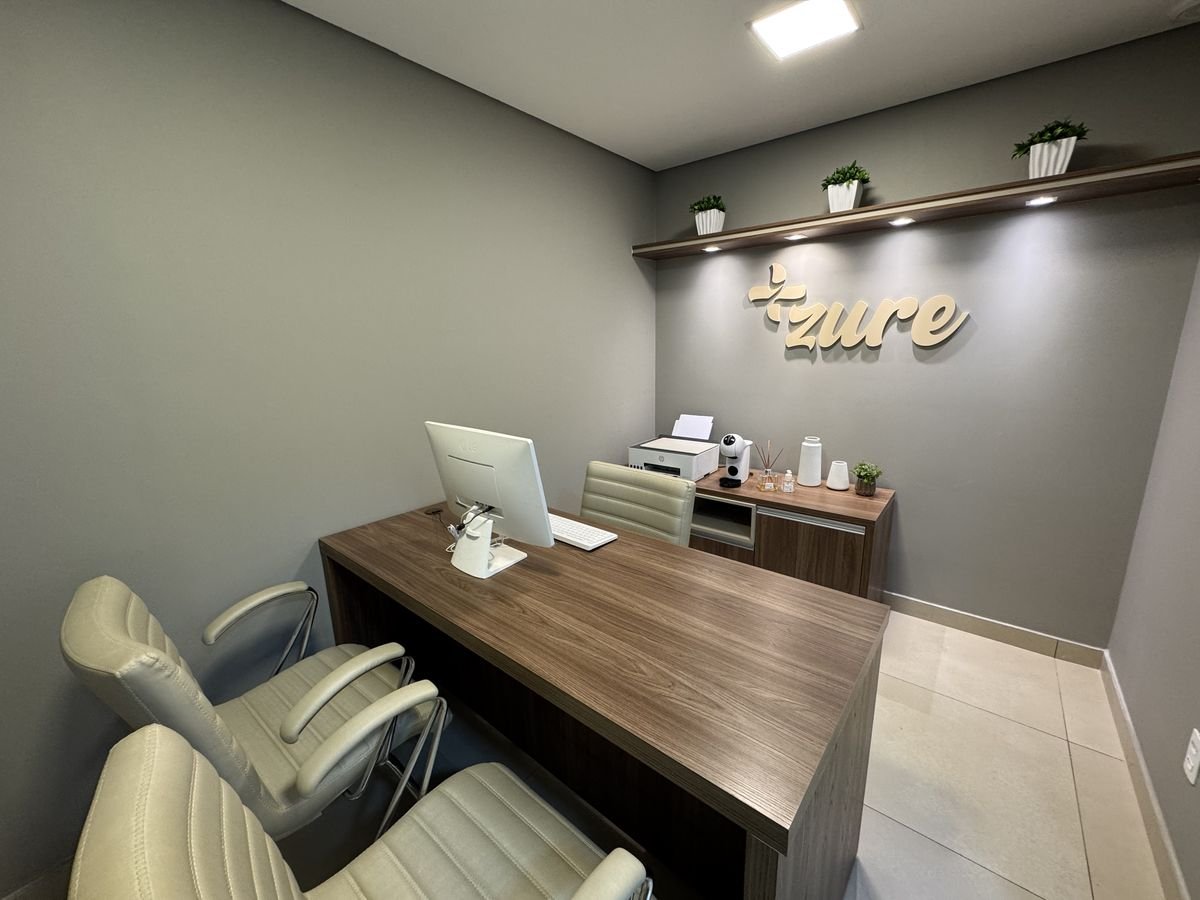 Sala de relacionamento da Zure, com bancada, computador e o logotipo da Zure na parede